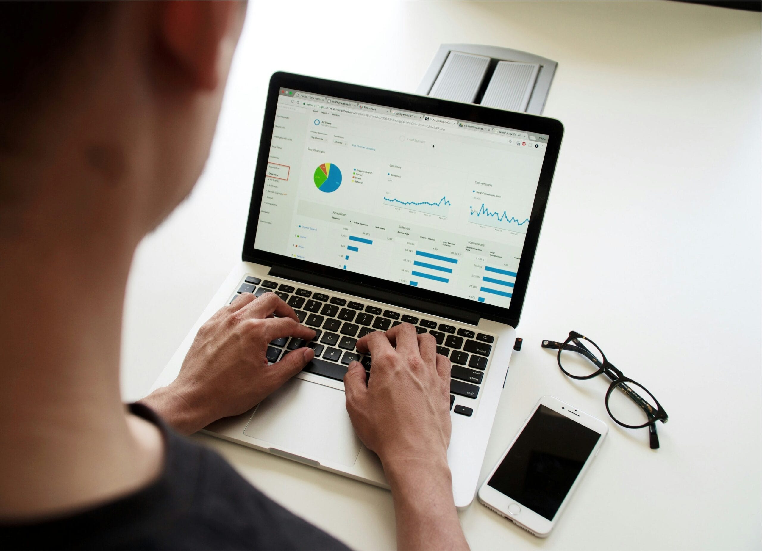 Individual using a laptop to analyze data with graphs and charts displayed on the screen.