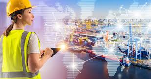 Woman wearing a hard hat and safety vest using a tablet while observing a port area.